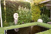 Clipped box hedge around reflective Infinity pool with contemporary statue 'Untitled' by artist Will Spankie and ceramic urn, white Astilbe and Beech hedging