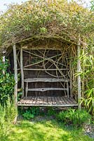 Handmade arbour with built in seat festooned  with Jasminum officinale.
