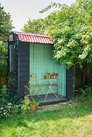 Mini garden pavilion with table and chairs and blue green interior.