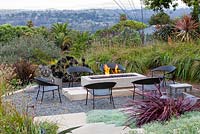 View of gas fired fire pit alight with outside seating. Debora Carl's garden, Encinitas, California, USA. August.