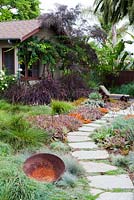View of garden path leading to summer house flanked by mixed beds containing succulents and ornamental grasses. Debora Carl's garden, Encinitas, California, USA. August.
