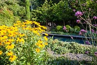 Formal pool edged with stone slabs and surrounded by box balls, pencil pine, Rudbeckia, Euphorbia cyparissias and slate mulch - July, Les Jardins de la Poterie Hillen