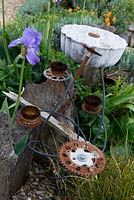 Seaside themed garden with ornamental sculpture made from found metal objects. Driftwood. Iris pallida. Gravel