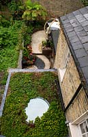 View down into garden and on to flat roof with round ceiling light and living sedum turf roof. 