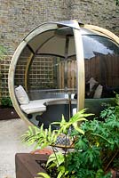 Large round wooden and perspex pod with seating and a table. Outdoor room