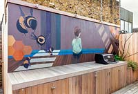 Painted mural by Lauren Mele behind bbq area of London roof terrace garden