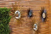 French sixties sunburst mirrors on wall in the garden. Ben De Lisi House and Garden, London