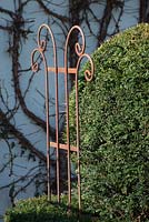 Taxus - yew topiary with decorative rusted support. St Francis Cottage