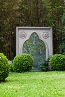 Large freestanding Gothic style cast cement frame with a mirror in front of a green screen.