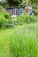 The Wild Garden where grass is allowed to grow long and bulbs are naturalised, with Debbie's studio in the corner.