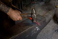 Paul Gilbert, blacksmith and sculptor, in his workshop making leaf figure from metal rod