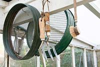 Garden tools - trowel, brush, sieve and fork hanging in greenhouse