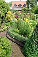 Summer garden with box hedging, flower borders with lillies and bottle lined path, Norfolk, England, July