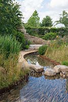 Rock stepping stones over a water rill, Cercidiphyllum japonicum with Prunus lusitanica and Panicum virgatum 'Northwind' -  Zoflora: Outstanding Natural Beauty, RHS Hampton Court Palace Flower Show 2016