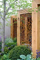 Rusty metal stenciled screen in timber frame. The Morgan Stanley garden for Great Ormond Street Hospital. RHS Chelsea Flower Show 2016