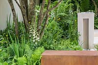 Garden of Mindful Living, a contemporary garden with limestone rill water feature, block and corten steel walls, multi-stemmed trees and shade borders with Blechnum tabulare, Hosta 'Devon Green', Matteuccia struthiopteris, Dryopteris erythrosora and Digitalis purpurea 'Dalmatian White'. The RHS Chelsea Flower Show 2016 - Designer: Paul Martin - Sponsor: Vestra Wealth LLP - GOLD