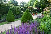 Formal English garden with clipped Yew pyramids, pleached Hornbeam hedging, Box balls, gravel path, long borders with mixed shrubs and perennials