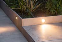 Lighting integrated into sandstone patio, illuminating steps leading to garden