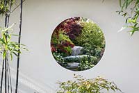 Circular view through garden building with stone boulders and Acer 'Bloodgood' - A Japanese Reflection, RHS Malvern Spring Festival 2016. Design: Peter Dowle and Richard Jasper, Howle Hill Nursery