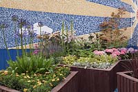 A sun, sky and cloud mosaic with raised planters filled with perennials in blue, pink and yellow. From here to there, RHS Tatton Flower Show 2011, Cheshire