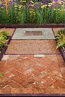 Mixed hard surfaces, brick paving in a herringbone design and painted wooden edges to beds. Garden: 'Nature Squared' at RHS Tatton Park Flower Show 2012