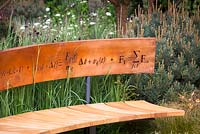 Curved bench seat decorated with mathematical symbols cut into band of copper forming back. The Winton Beauty of Mathematics Garden, RHS Chelsea Flower Show 2016