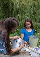 A girl drawing a face onto a galvanised bucket