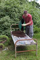 Cover the soaked newspaper and cardboard with 4 to 5 inches of compost