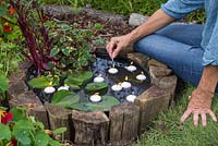 Lighting floating tealight candles in the barrel pond
