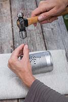 Use the hammer and nail to create the pattern on the tin can
