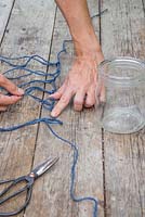 Cut one long length of string and loosely attach the 7 to 8 pieces of string to it