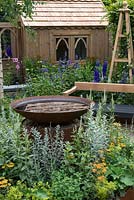 An Arts and Crafts inspired garden with a water feature, handmade bench and shed. A Summer Retreat designed by Laura Arison and Amanda Waring. RHS Hampton Court Flower Show 2016
