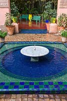 Low fountain and pool of water with blue and green glazed tiles in the Jardin Majorelle. Created by Jacques Majorelle and further developed by Yves Saint Laurent and Pierre Bergé, Marrakech, Morocco
