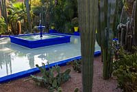 Square, blue painted fountain and pool with cacti in the Jardin Majorelle. Created by Jacques Majorelle and further developed by Yves Saint Laurent and Pierre Bergé, Marrakech, Morocco