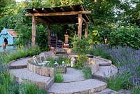The Lavender Garden. Lavender along circular walkway, sunken seating area with chairs. Rustic hut with cut lavender for infusion. Designers: Paula Napper, Sara Warren and Donna King. Sponsors: Shropshire Lavender. RHS Hampton Court Palace Flower Show 2016