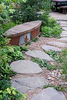 The WWT Working Wetlands Garden. Unusual garden bench along stepping stone path. Designer: Jeni Cairns, Sponsors: WWT. RHS Hampton Court Palace Flower Show 2016