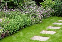 Lawn with a stone paving slab path dug into the surface to allow the use of a lawn mower over the top