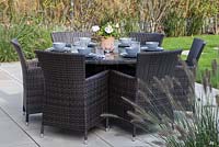 Patio dining table set ready with a potted Pelargonium as the centrepiece