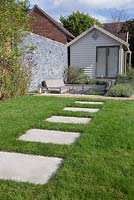 Stone slabs laid into the garden lawn, leading to sunken seating area and a summer house