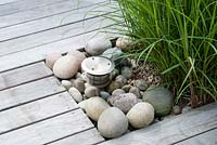 Contemporary hard wood deck with contrasting texture of rounded pebbles and Miscanthus sinensis  