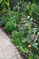 Natural stone cobble sett curved path with mixed planting and metal sphere balls sculpture