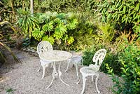 Seating are surrounded by large leaved foliage plants including Viburnum rhytidophyllum, Tetrapanax papyrifer, trachycarpus and phormiums.