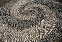 Pebble mosaic made using contrasting white and grey stones on edge to form a whirlpool effect.