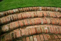 Curving steps linking a patio to a lawn built from recycled bull-nosed bricks. Design: David Green and Elaine MacKenzie.