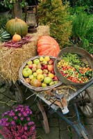 Late summer and autumn harvest of fruits and vegetables gathered on a flat topped farm cart including apples, pears, peppers, tomatoes, beans, pumpkins and squash