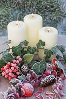 Candle lit display with frosted Ivy foliage, Skimmia berries and Pine cones
