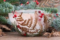 A frozen candle bowl with a lit tealight. Constructed from Fern foliage, Pine foliage and berries of Ilex verticillata