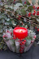 A frozen Jelly mould candle bowl with a lit candle. Constructed from Pine foliage, Eucalyptus and Ilex verticillata berries