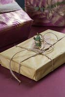 A wrapped present with a natural gift tag of Eucalyptus and gold spray painted fern foliage