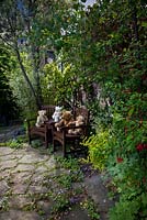 Bears on a bench in the Bear Shop Gardens. Surorunding plants include Fuchsias magellanica hybrids and Campanula poscharskyana, 
